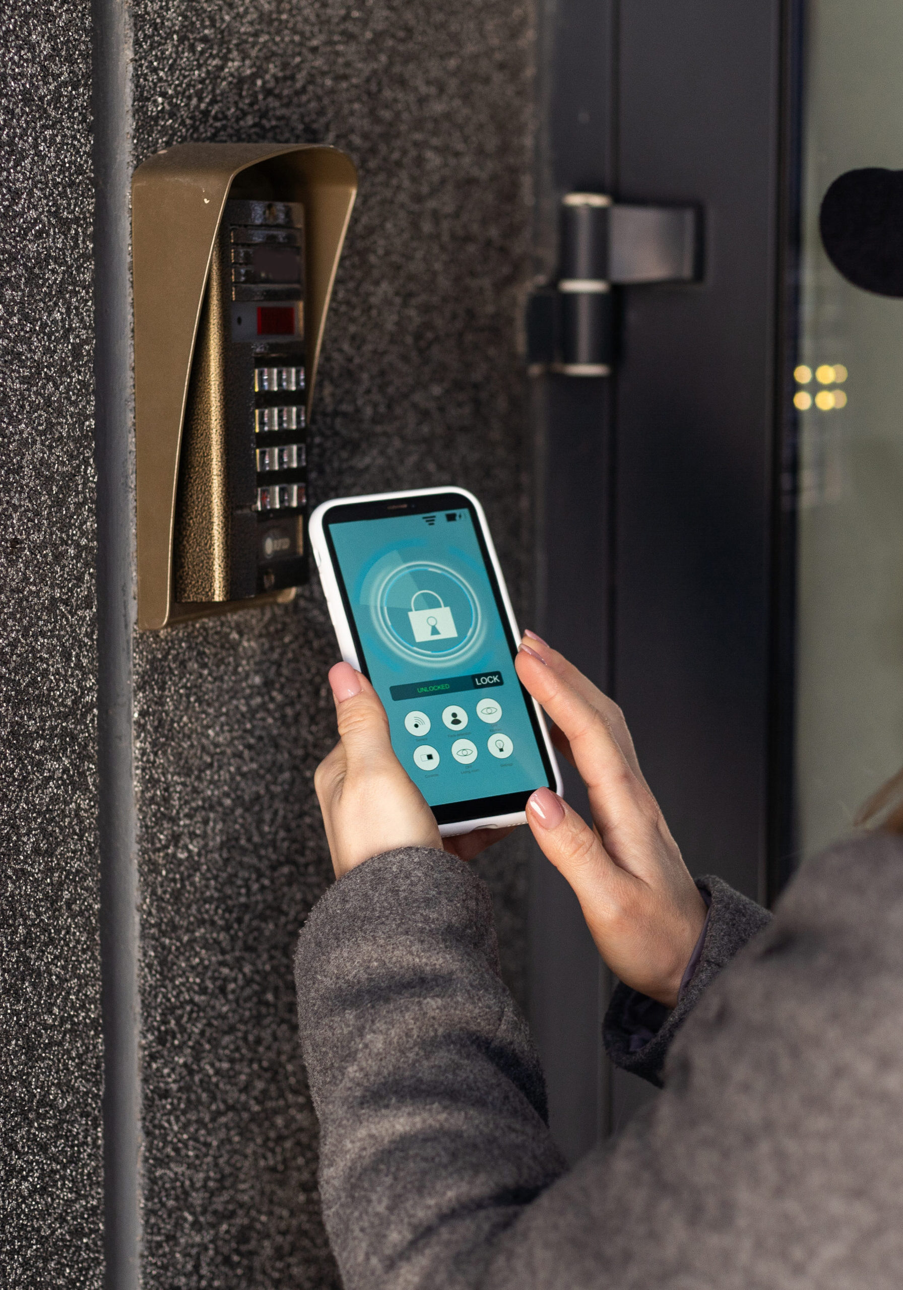 woman uses smartphone to open the door of his house. High quality photo